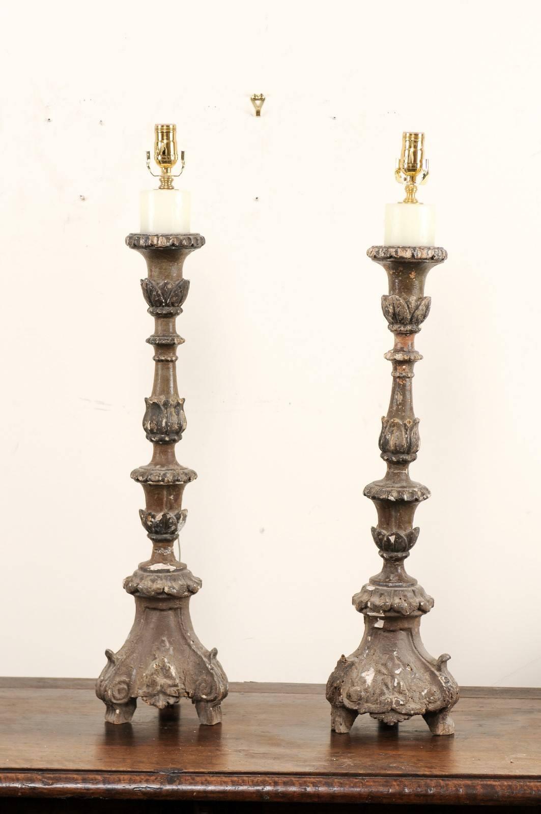 A pair of Italian 18th century carved wood altar sticks made into table lamps. This pair of Italian table lamps has been fashioned from antique altar sticks with gesso and old paint over carved wood. They feature beautifully carved bodies with leaf