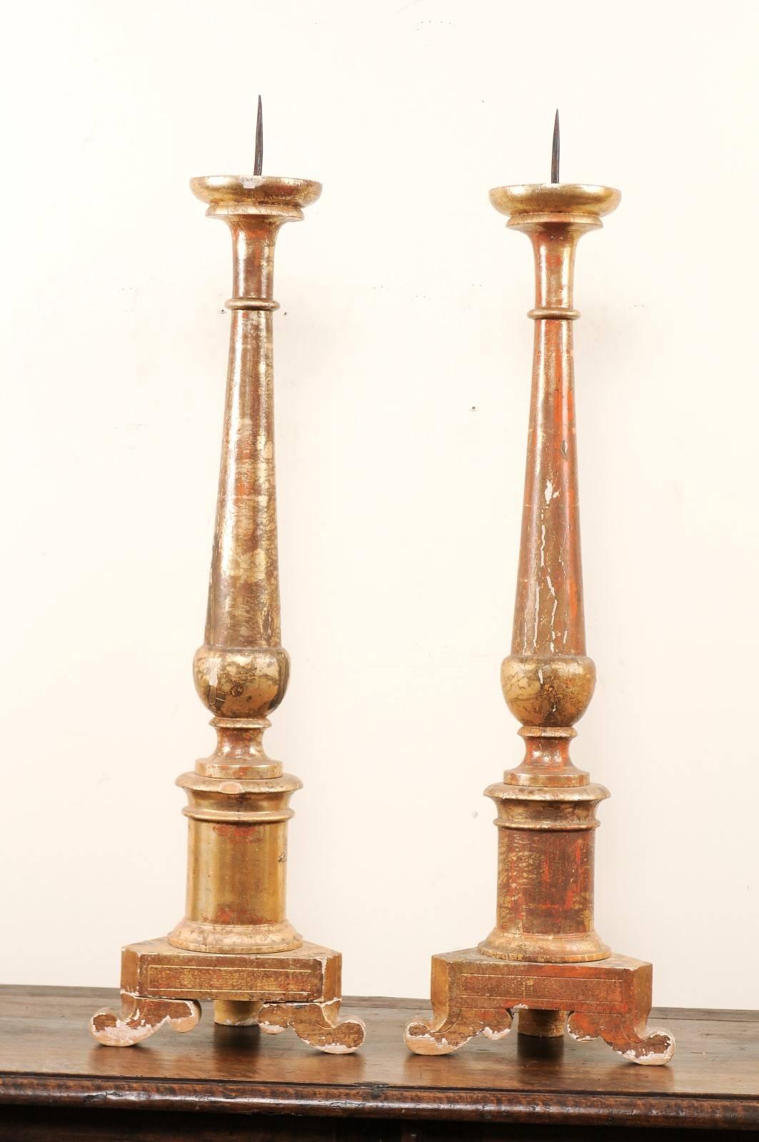 Pair of Italian, 19th century gilded altar sticks. This pair of antique Italian altar sticks are more than 3 ft tall and each feature a beautifully turned central column which has been lifted up on a triangular-shaped base and three curved bracket