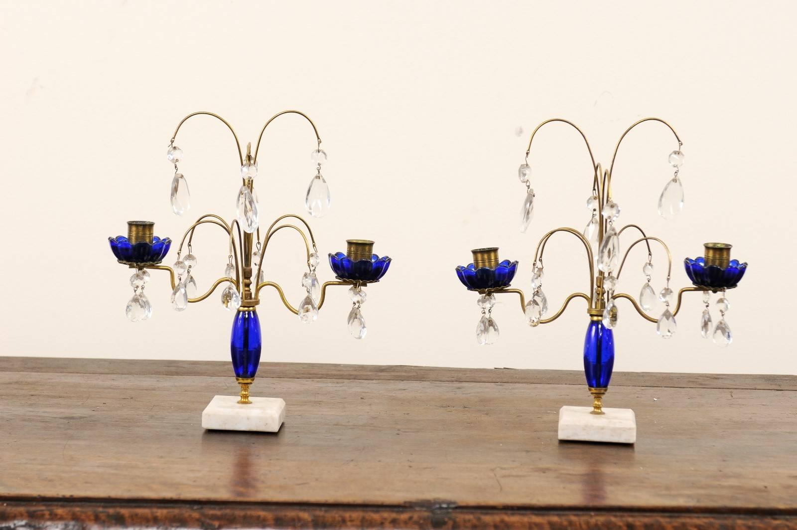 A Pair of 19th century Swedish crystal and cobalt glass girandoles. This pair of neoclassical Swedish two light girandoles each feature a central column of cobalt blue glass with matching cobalt bobeches. There are various crystals freely hanging