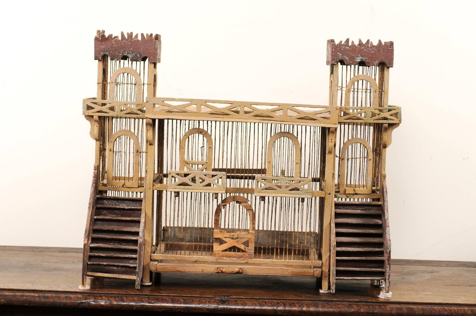 An Italian mid-20th century wood bird cage. This vintage Italian birdcage has been lovingly handcrafted and features a two storied main structure which is flanked by twin towers and entry stairs. There are x-stylized window boxes and upper railing