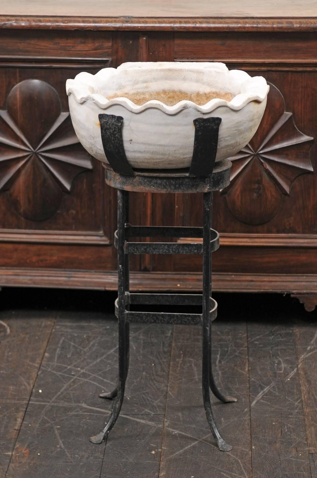 A 19th century Italian marble sink on metal stand. This antique sink with it's black forged iron stand was originally used as a holy water container. The oval-shaped sink is hand-carved marble with a beautifully scalloped rim. The iron stand is