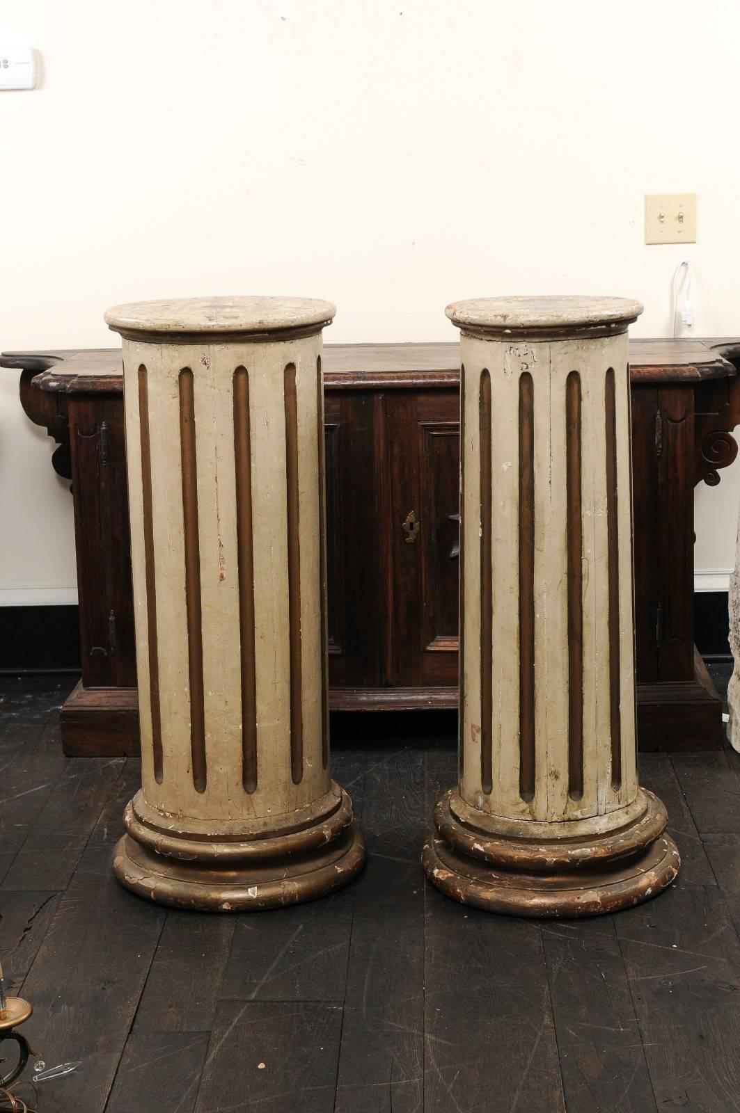 A pair of 19th century French nicely tapered and fluted columns.  This pair of carved wood, round-shaped columns each are fluted and gently taper to their wider, circular bases.  They retain their original paint, which is nicely aged and chipping,