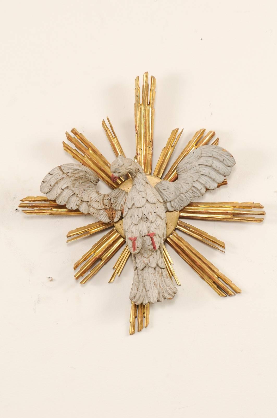 A 19th century Italian altar piece fragment. This antique fragment was once part of an Italian altar piece. This hand-carved fragment depicts a painted dove, with wings spread and head tilted to its side, atop a gold gilt sunray bursting out from