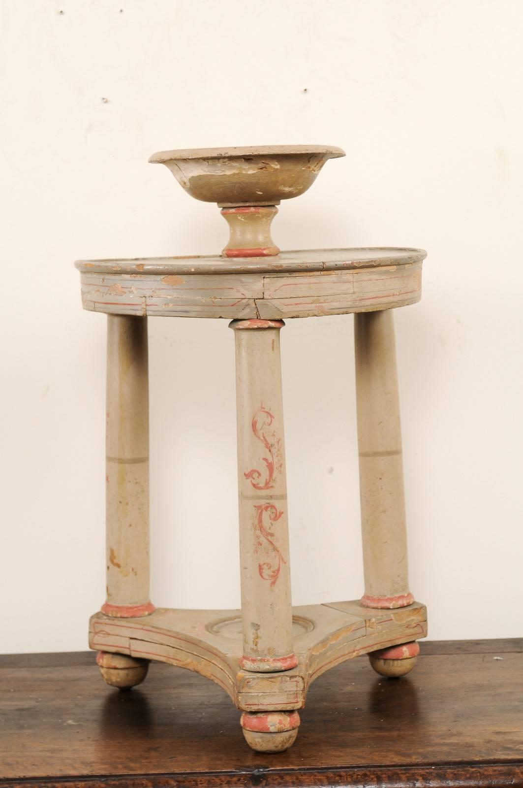A vintage Italian two-tiered gueridon table. This unusual two-tiered gueridon table features a an urn decorated top which sits upon an upper round-shaped table, three round legs braced by the lower, more rectangular-shaped bottom and ball feet. The