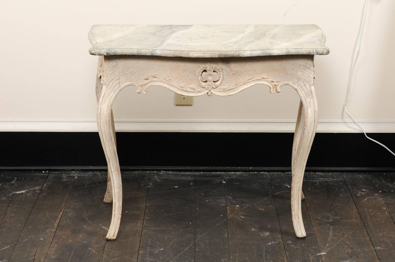 An 18th century Swedish wooden side table. This exquisite antique Swedish side table features a hand-painted faux-marble top, and scalloped apron which has been carved with a fine cross-cross and dotted pattern. This table has a pierced carving at