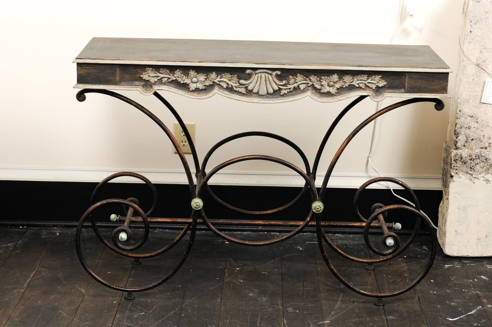 Mesa de panadero francesa de época con tablero de madera pintada y base de hierro. Esta caprichosa mesa francesa presenta un tablero de madera pintada, con motivos florales y de conchas festoneados y tallados sobre el centro delantero de su faldón.