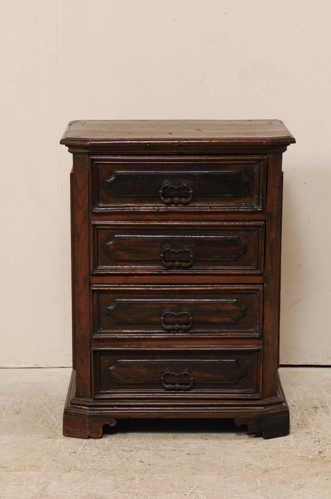 An Italian late 18th century four-drawer cabinet. This antique Italian chest of rich walnut features beautifully carved panelled drawers and side panels. The top is bevelled, or chamfered, and the four drawers are adorned with decorative pulls at