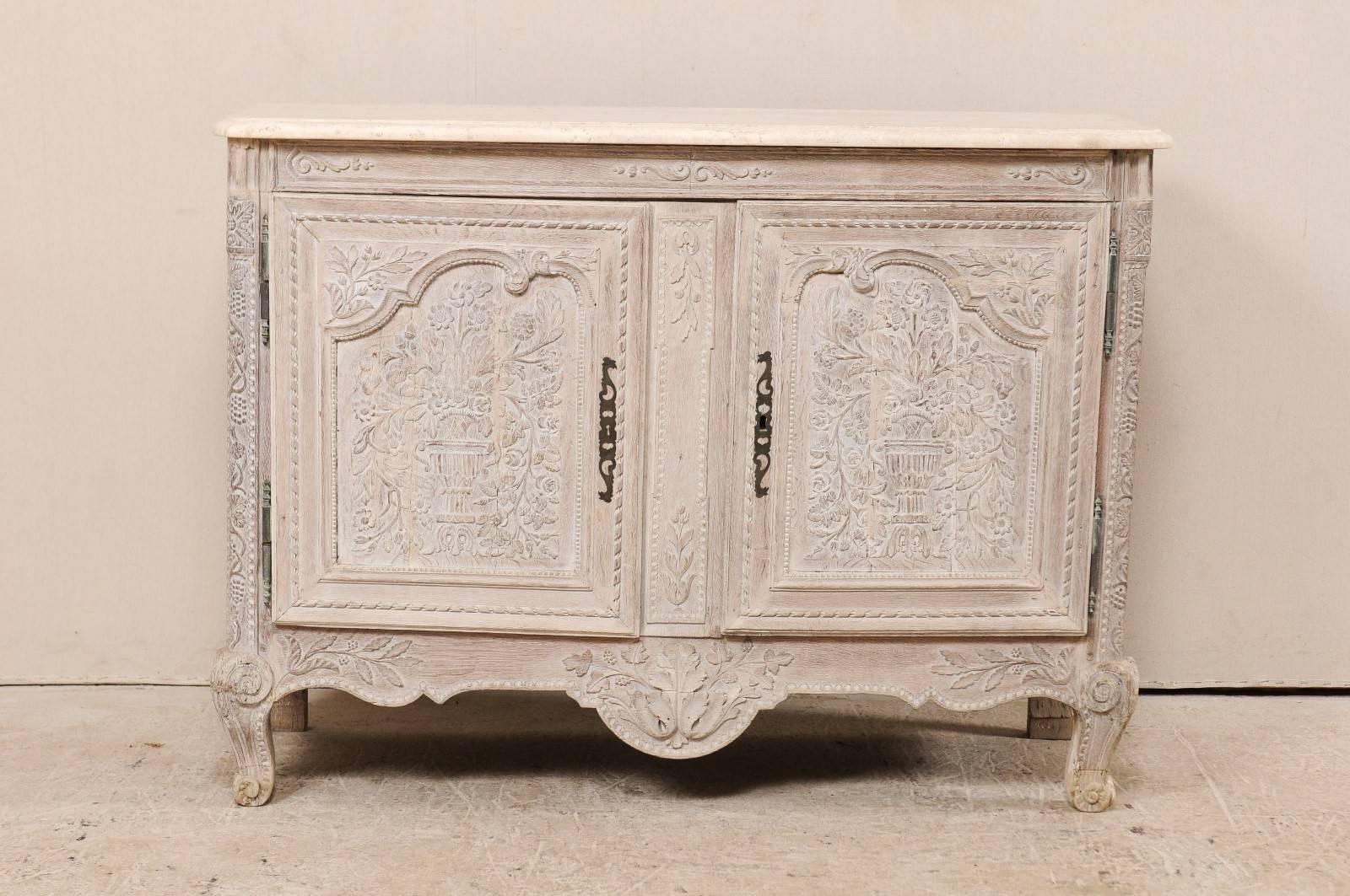 A French ornately carved wood cabinet with marble top from the early 20th century. This antique French buffet has unusually elaborate carvings which decorate it's front. The two paneled doors each feature finely detailed and intricate carvings