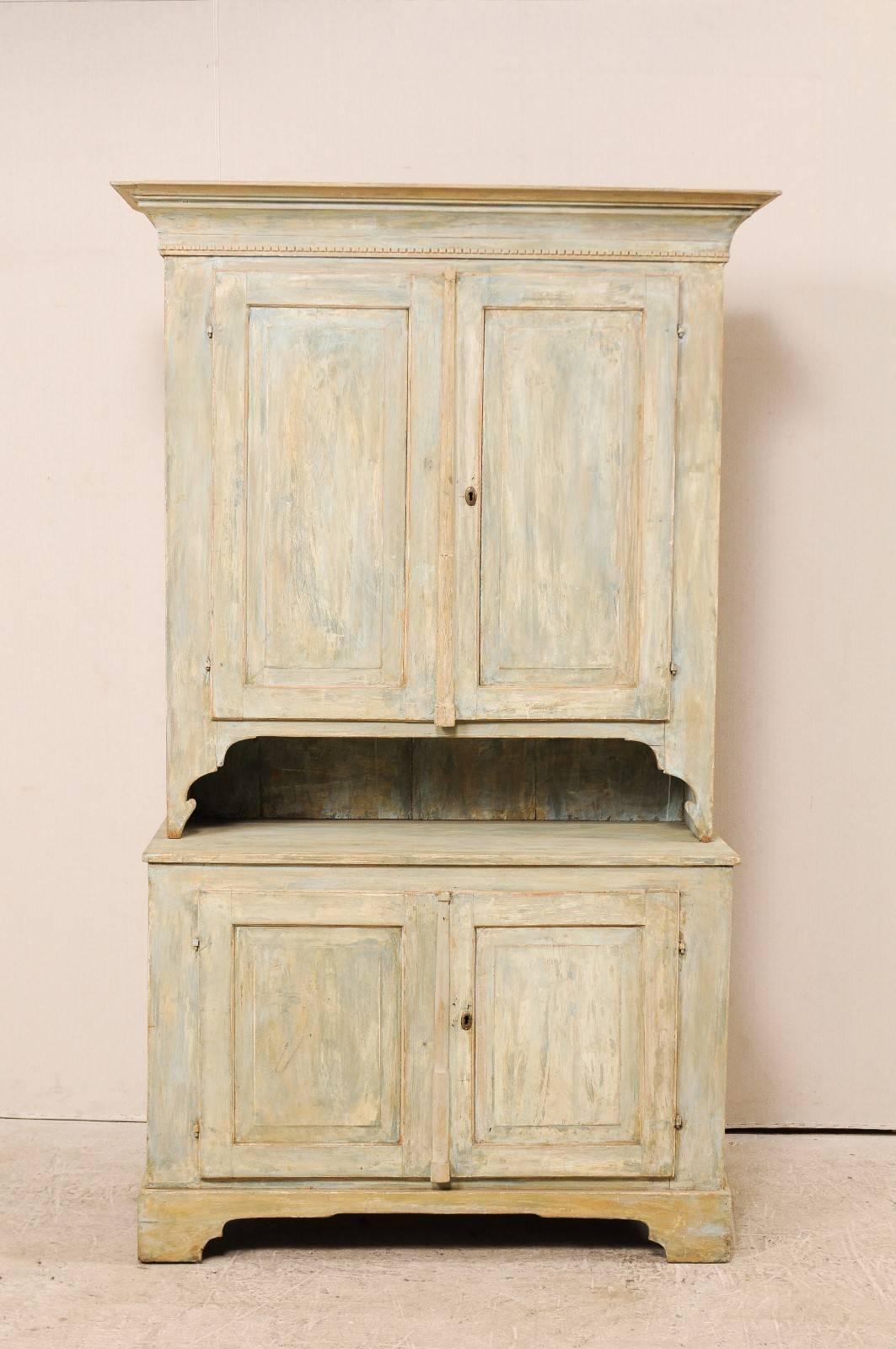 A 19th century Swedish Karl Johan painted wood two-piece cabinet. This tall antique Swedish cabinet has a two door upper case which is set back upon a shelved base, two door cabinets. This cabinet features four raised panel doors, traditional