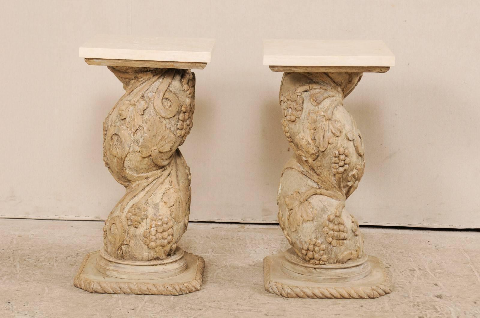 A pair of Italian 19th century carved wood pedestal tables with marble tops. This pair of antique Italian tables feature square marble tops with ornately carved wood pedestal bases. The thickly twisted shaped bases are each carved in a scrolling