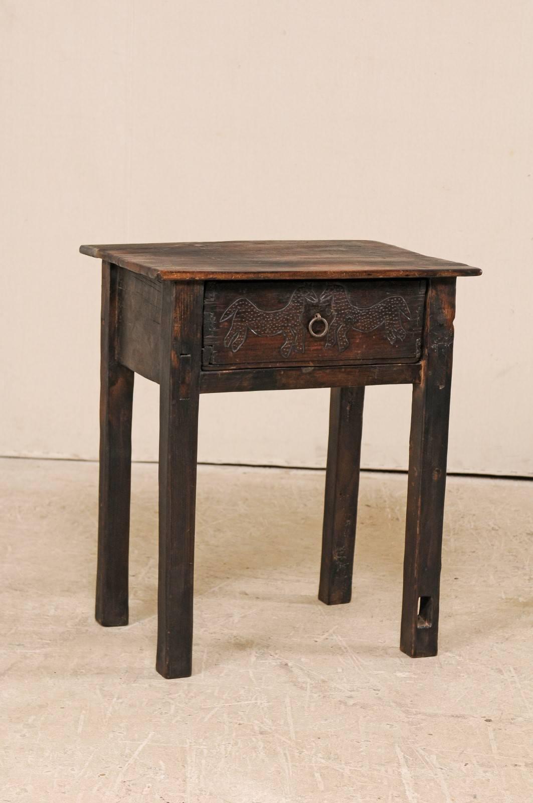 A Guatemalan side table from the early 20th century. This Guatemalan rectangular-shaped side table features a single drawer, which has two primitively carved horses, decorated with punched dotting, facing each other and a simple ring pull between