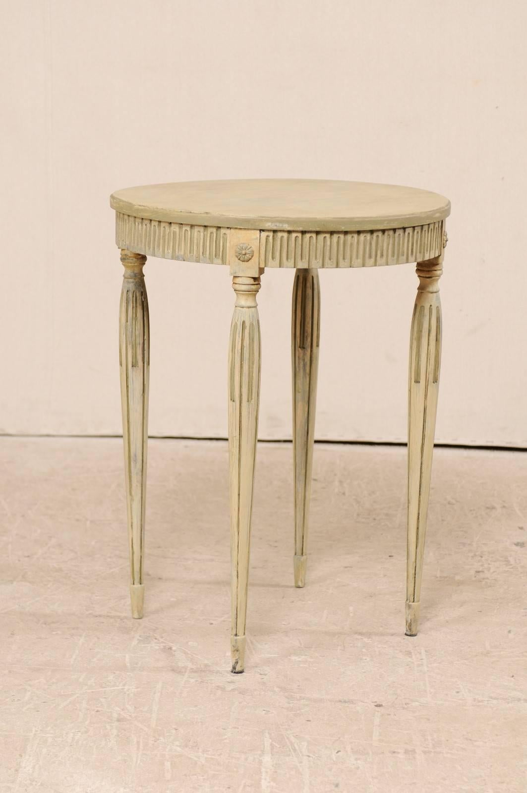 A vintage Swedish carved and painted wood occasional table. This sweet little Swedish side table features a circular-shaped shaped top, nicely carved apron, and rosettes carved just above each leg. The table is raised nicely on four rounded legs,