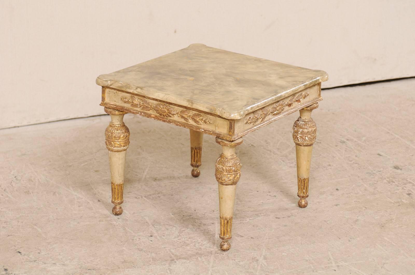 An Italian 18th century gilded and painted coffee table. This Italian antique coffee table has a wonderfully carved apron, adorn in a floral motif on all sides. The hand-painted, faux-marble top is a later addition, which adds much interest to the