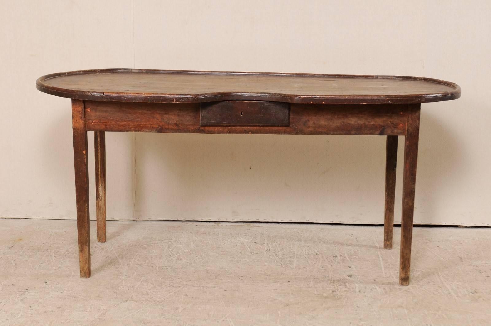 A Spanish late 19th century oval-shaped gaming table. This antique Spanish gaming table features a nice oval shape, with dealer seating cut-out and single drawer. The top has rounded raised edges, a chip slot cut-out above the drawer below, and a