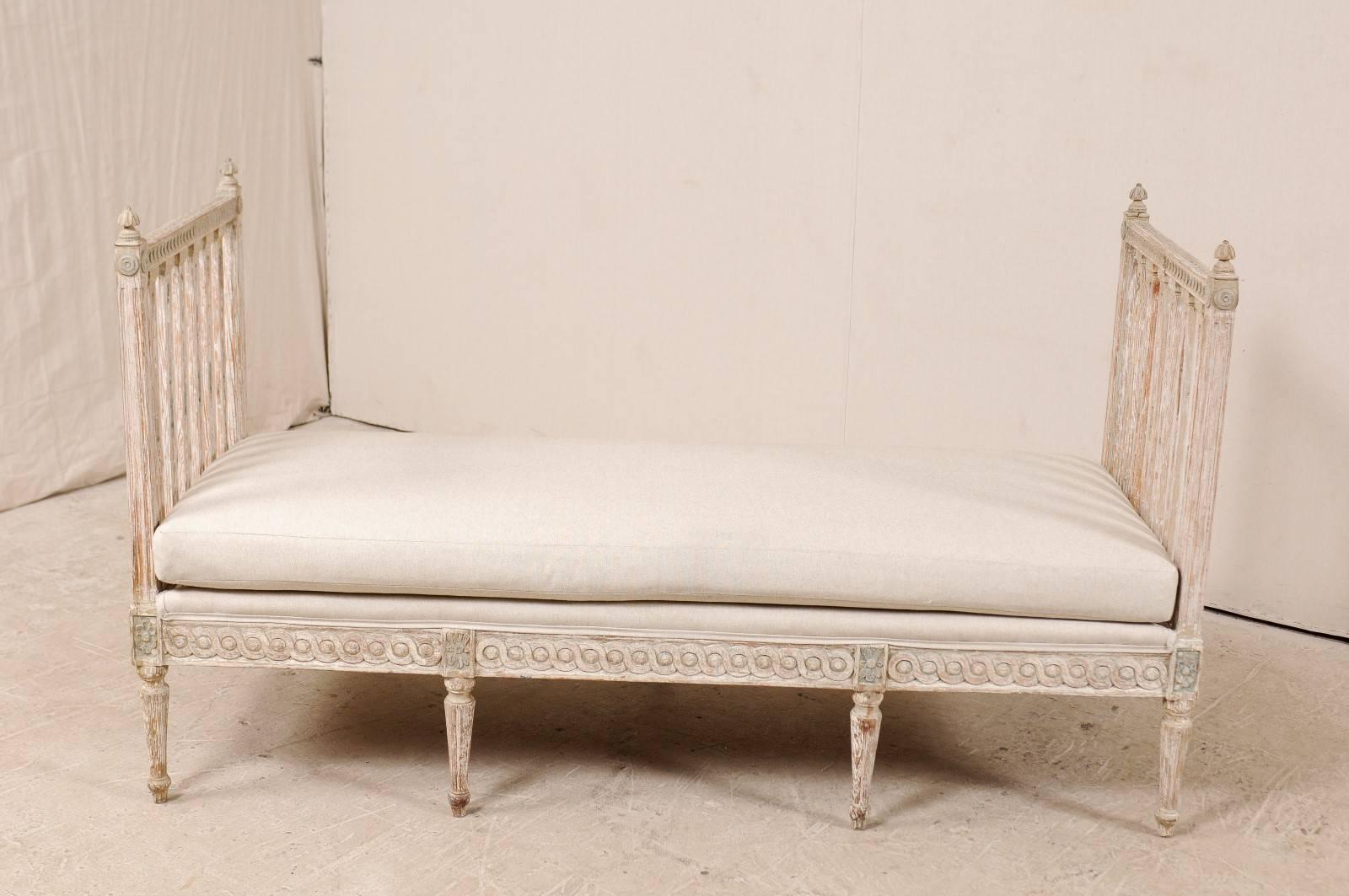 A Swedish period Gustavian daybed or sofa bench from the late 18th or early 19th century. This Gustavian daybed features high splat sides, attractively carved like pierced columns, and flanked with a decorative finial at each side post. There are