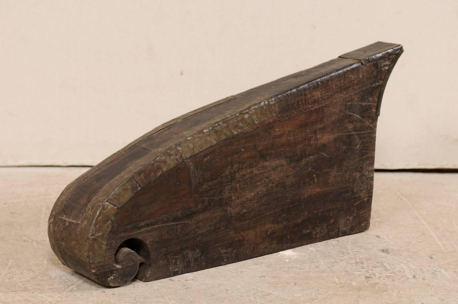 A South Indian (Kerala) wooden boat prow from the mid-20th century. This hand-carved boat prow from Kerala is adorn with curling volute and cut metal banding accented along it's top sides, which has a beautiful salt water patina. These raised prows