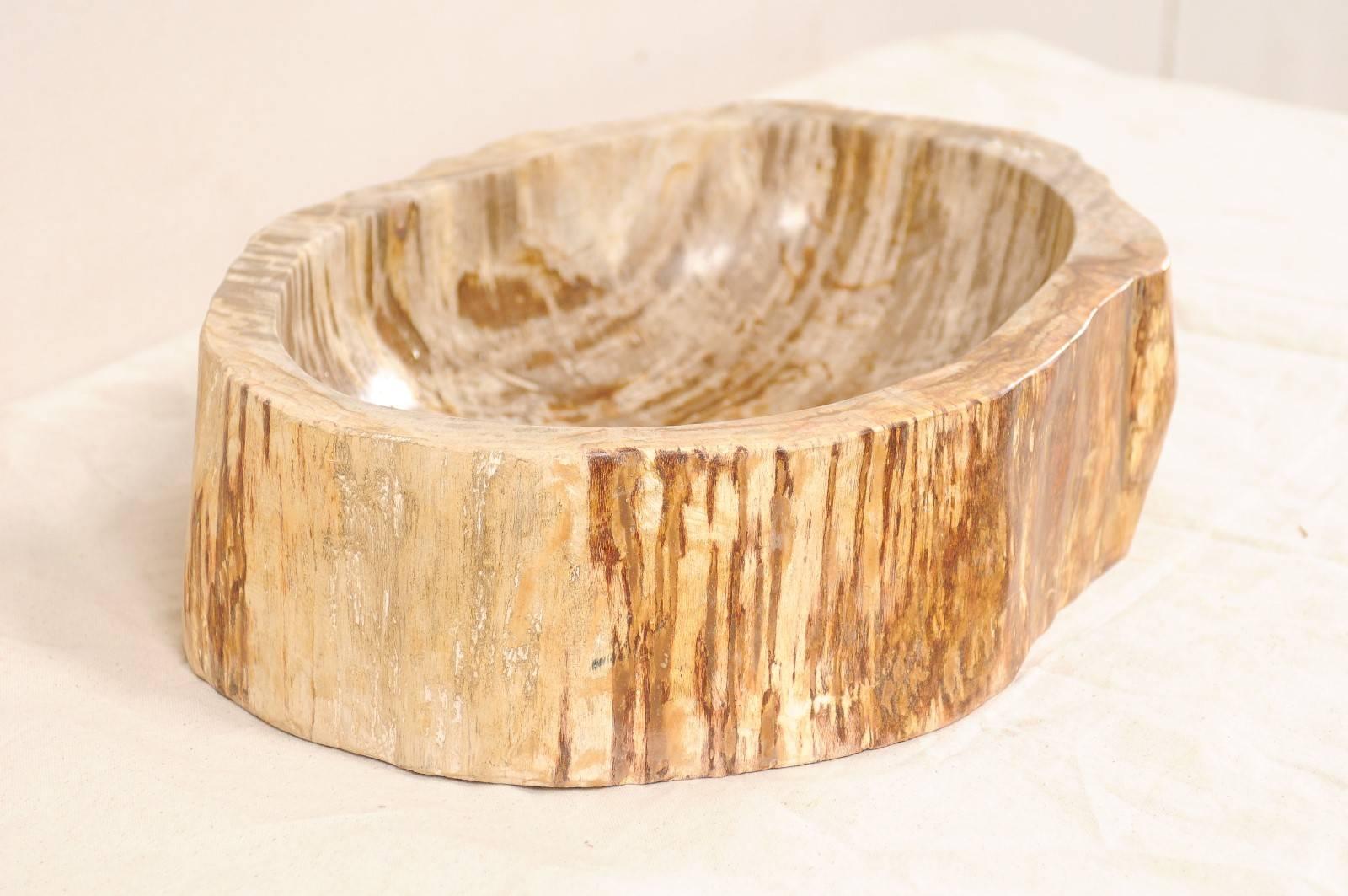 A petrified wood sink. This oval-shaped petrified wood sink has primary colors in a taupe and beige, with richer brown and rust tones. While the interior of the bowl has been polished, the surround has been left unpolished. Petrified wood is the