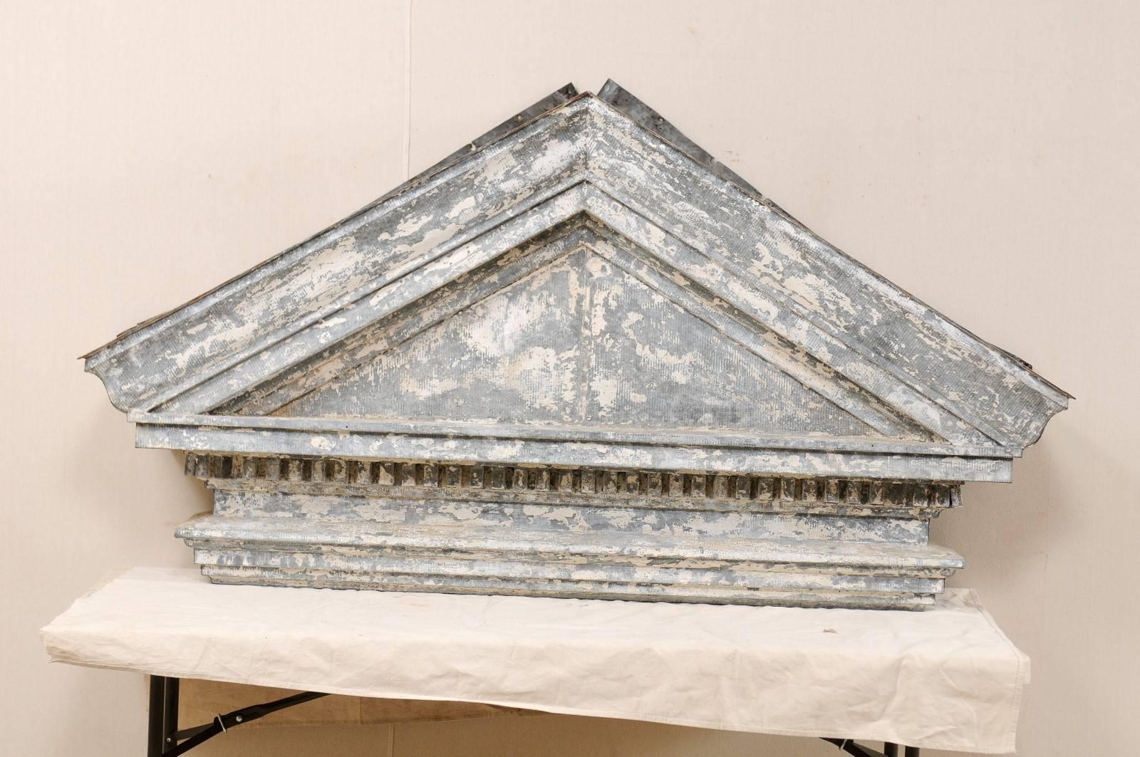 An American zinc pediment from the 19th century. This antique zinc pediment, with it's overall triangular-shape, once adorn the entry exterior of an old building. This piece is nicely aged, with beautiful patina throughout. This pediment features
