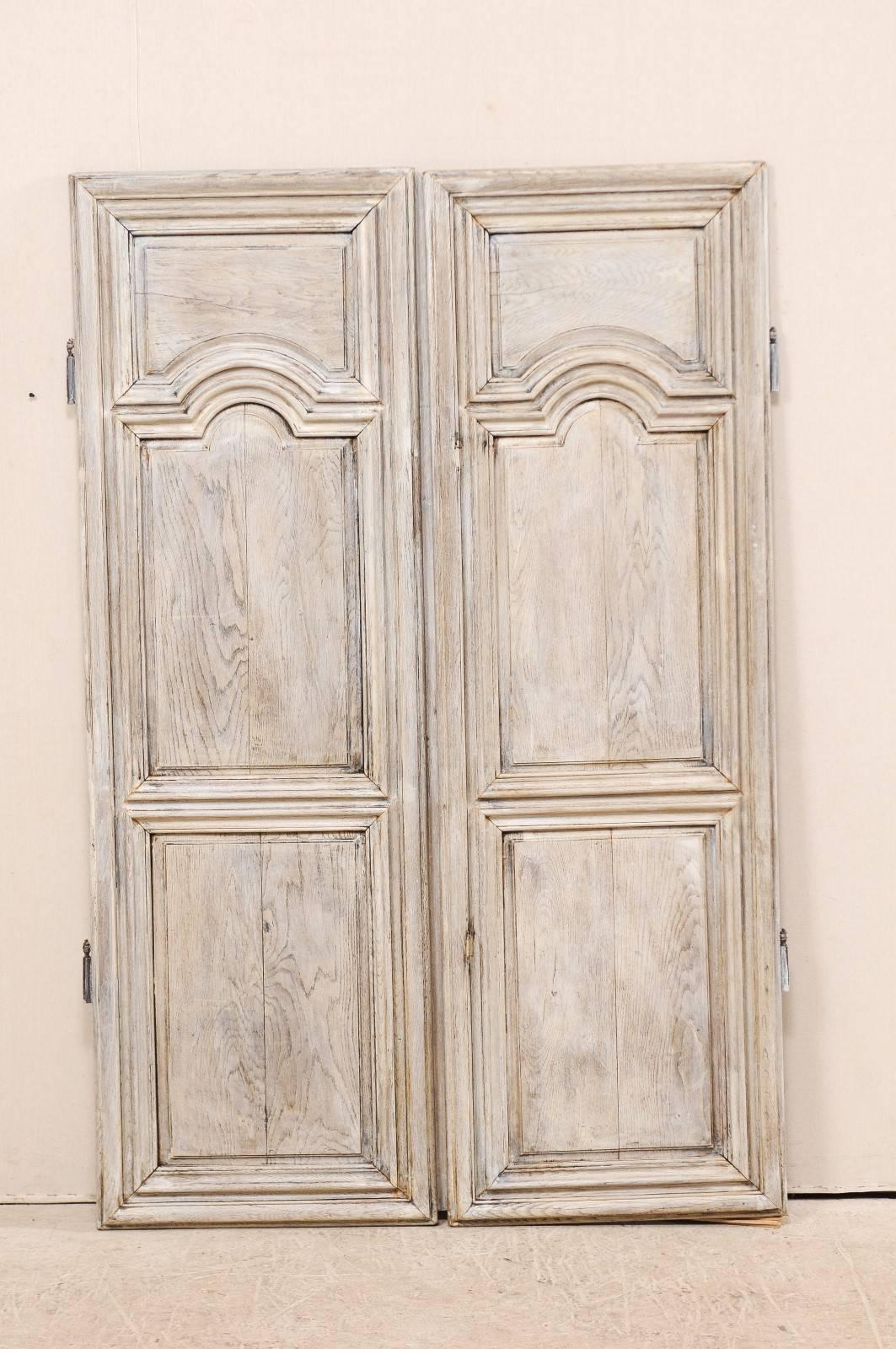 A pair of shorter-sized, 19th century, French doors. This cute pair of antique French doors have three raised panels on their fronts, with the upper and middle panels featuring convex and concave half-moon designs, which harmoniously fit together