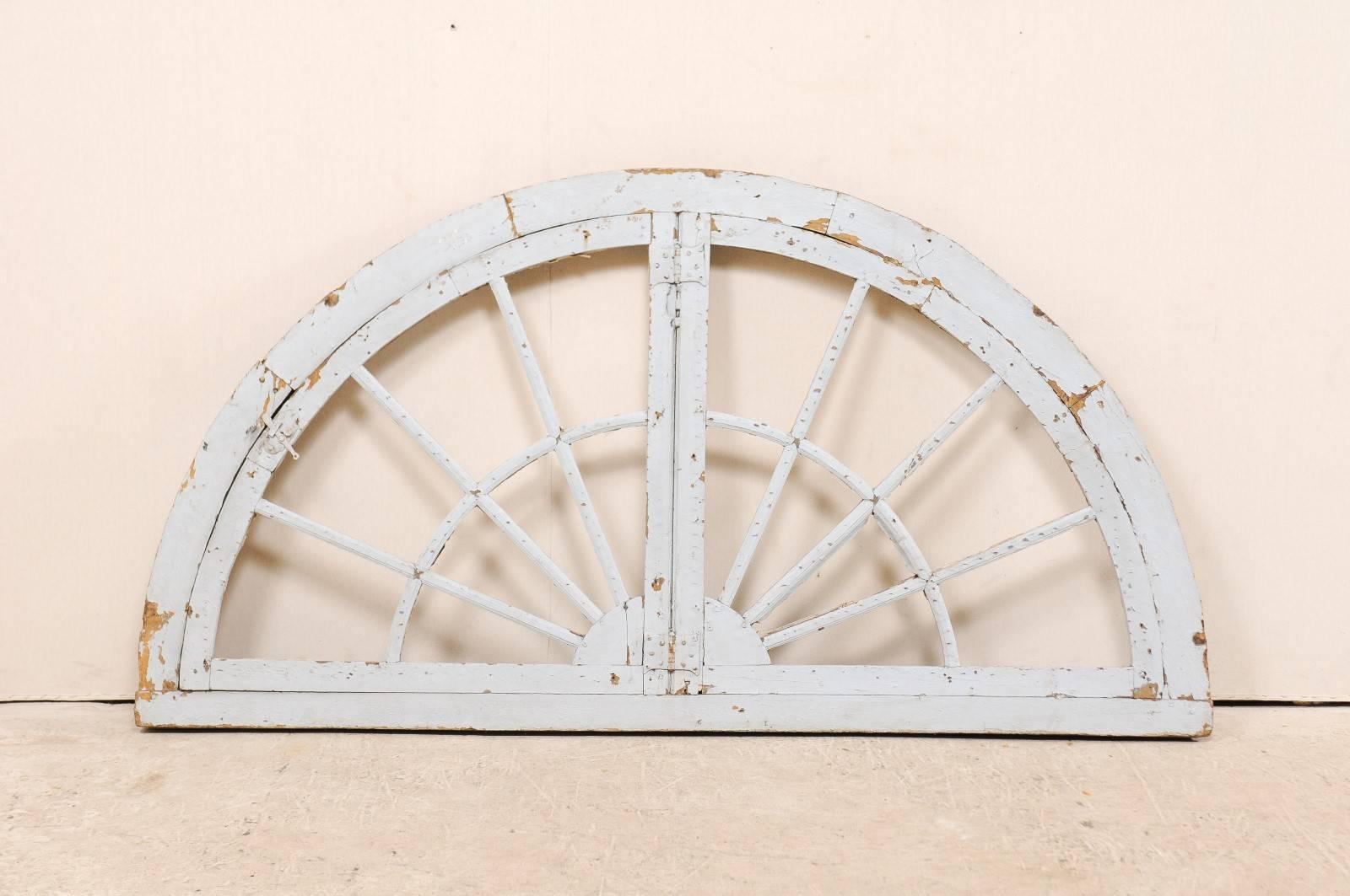 A large-size French 19th century painted wood half round window casement. This gorgeous antique French half-moon window features a painted wood casement, with muntins reminiscent of sun rays, reaching upwards from the bottom center. The casement is