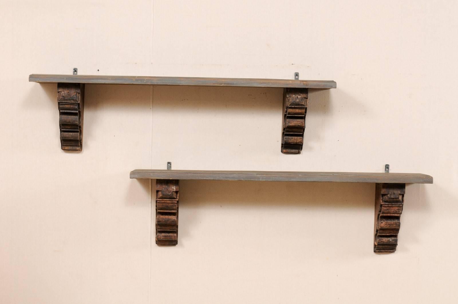 A pair of Italian style wooden shelves fashioned from old carved brackets. This pair of shelves feature beautifully carved brackets, supporting the underside of each shelf on either end. The tops have a charcoal wash over wood grain. These shelves