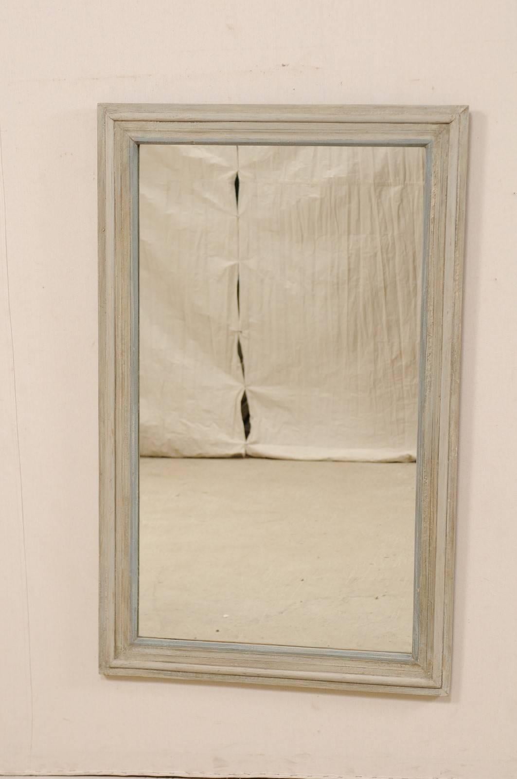 A vintage American painted wood mirror. This American mirror, with it's simple and clean lines, has an overall rectangular shape with a molded surround. The mirror is primarily a pale grey/blue with some darker grey and a lighter blue accent along