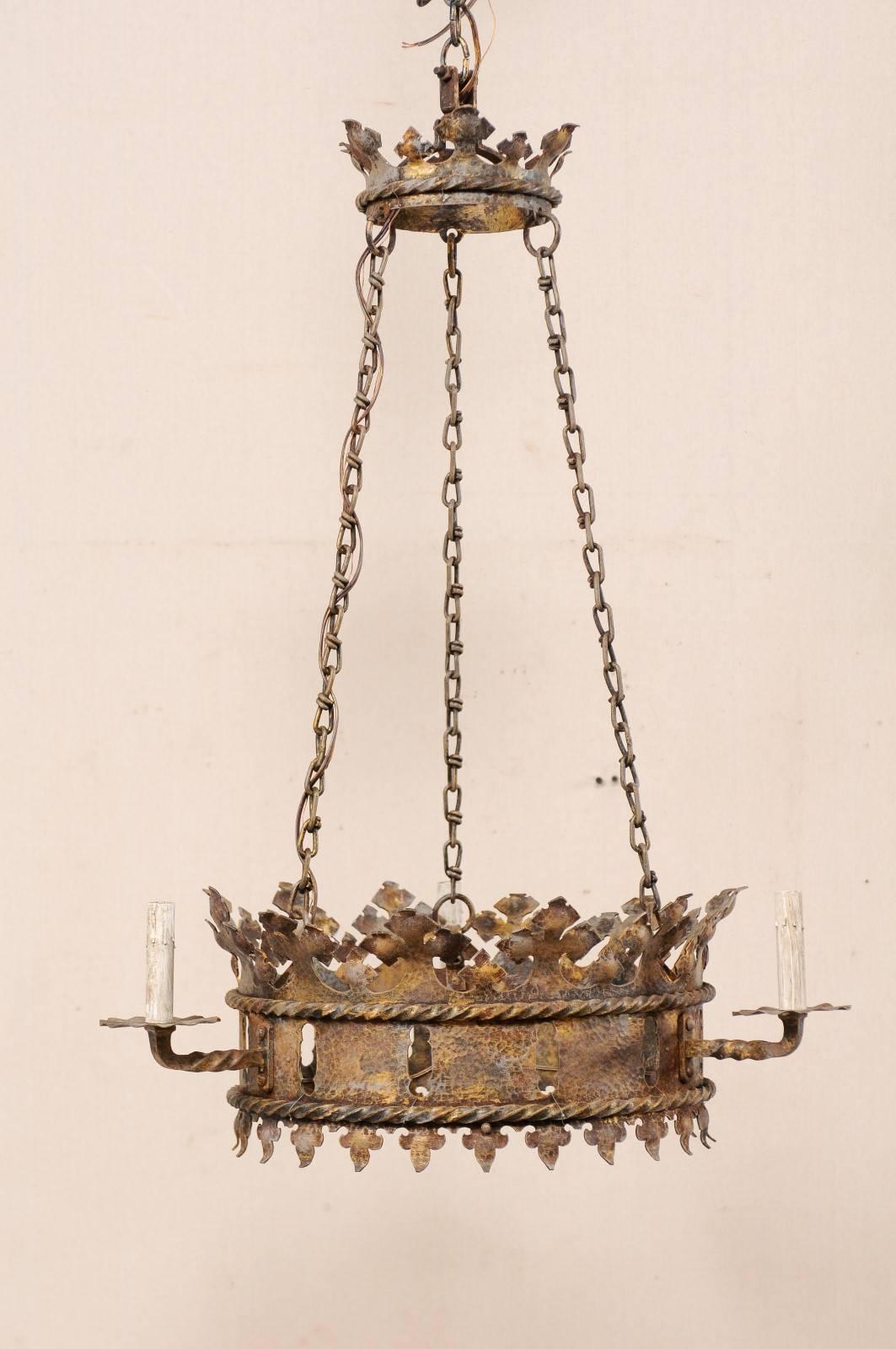 A French midcentury ring-shaped iron three-light chandelier. This elegant French chandelier from the mid-20th century features an open circular base, which resembles that of a crown, has been elaborately stylized with piercings, roped-trimmings,
