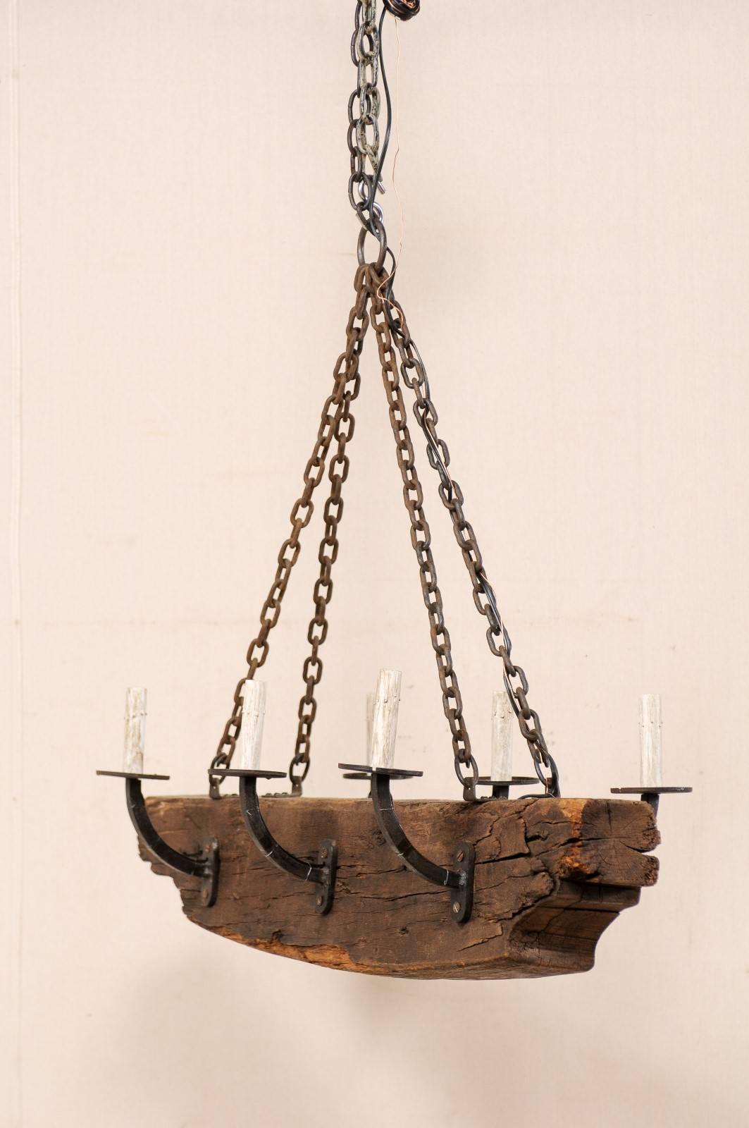 A vintage French six-light rustic beam and metal arms chandelier. This French mid-20th century chandelier has a central wooden beam with six forged iron arms, three at each opposing side. The six arms are simply designed, gently rising up and away