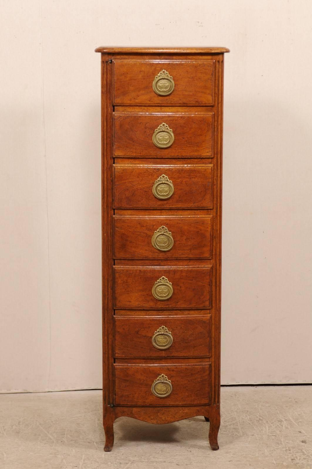 A French fruit wood cabinet from the early 20th century with faux drawers front. This antique French cabinet features a semainier (or semaniere) designed front, which is actually seven faux drawers that top as a single door to reveal an open cabinet