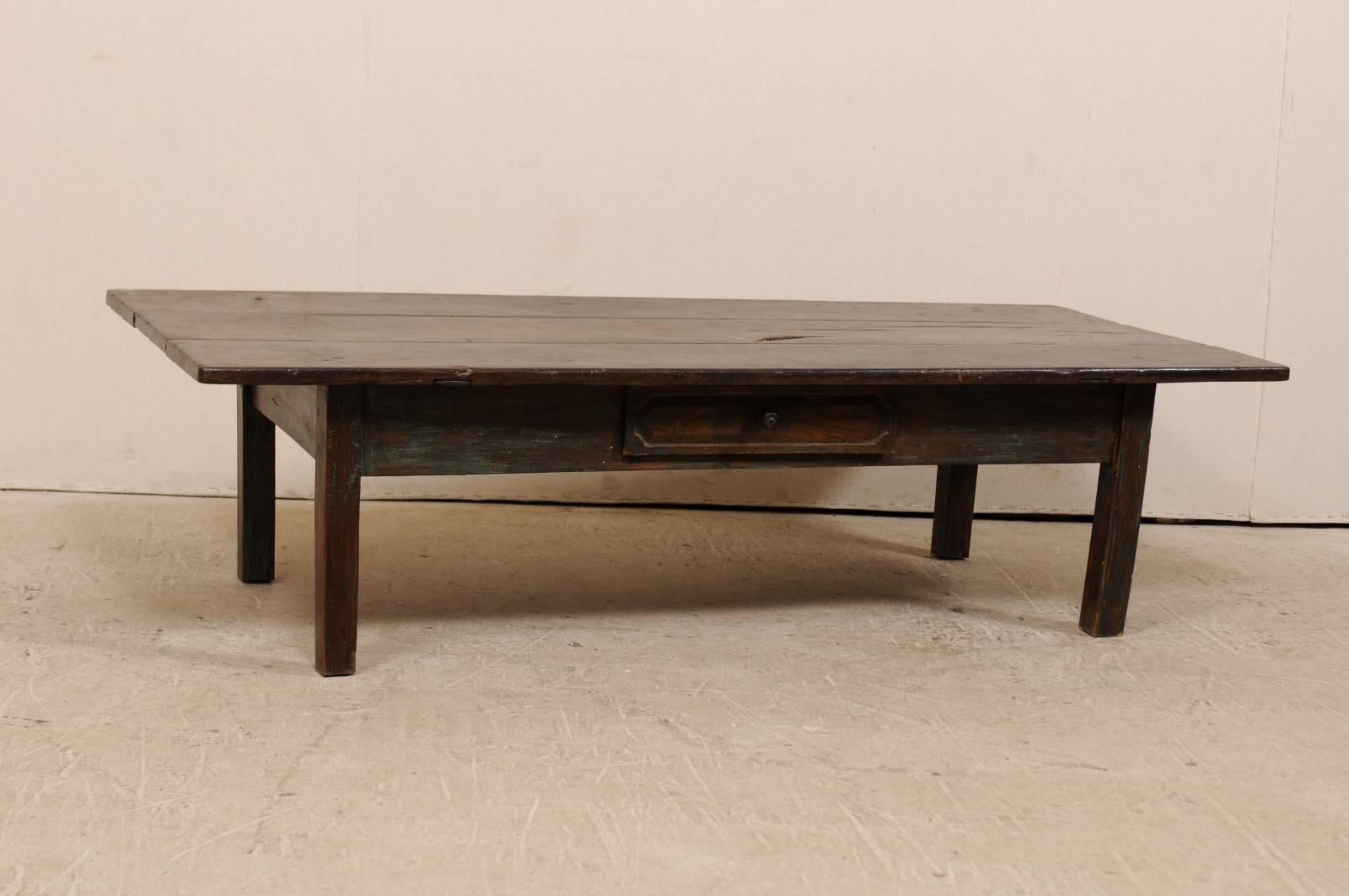 A 19th century Brazilian wood coffee table. This Brazilian table, from the late 19th century, features a single drawer, overhanging top, straight skirt, and is raised up on squared legs. The table is peroba wood (a tropical native hardwood, 35%
