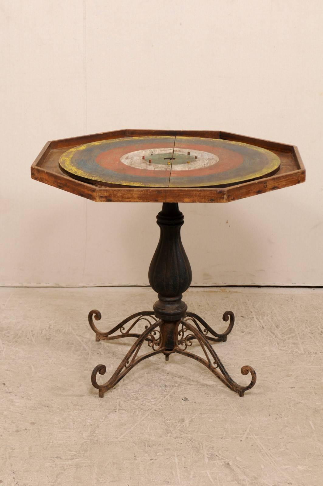 An American gaming table from the late 19th-early 20th century. This turn of the century game table features a painted wood crokinole game board top which rests upon an iron pedestal base with quadripod feet. The crokinole game is thought to have