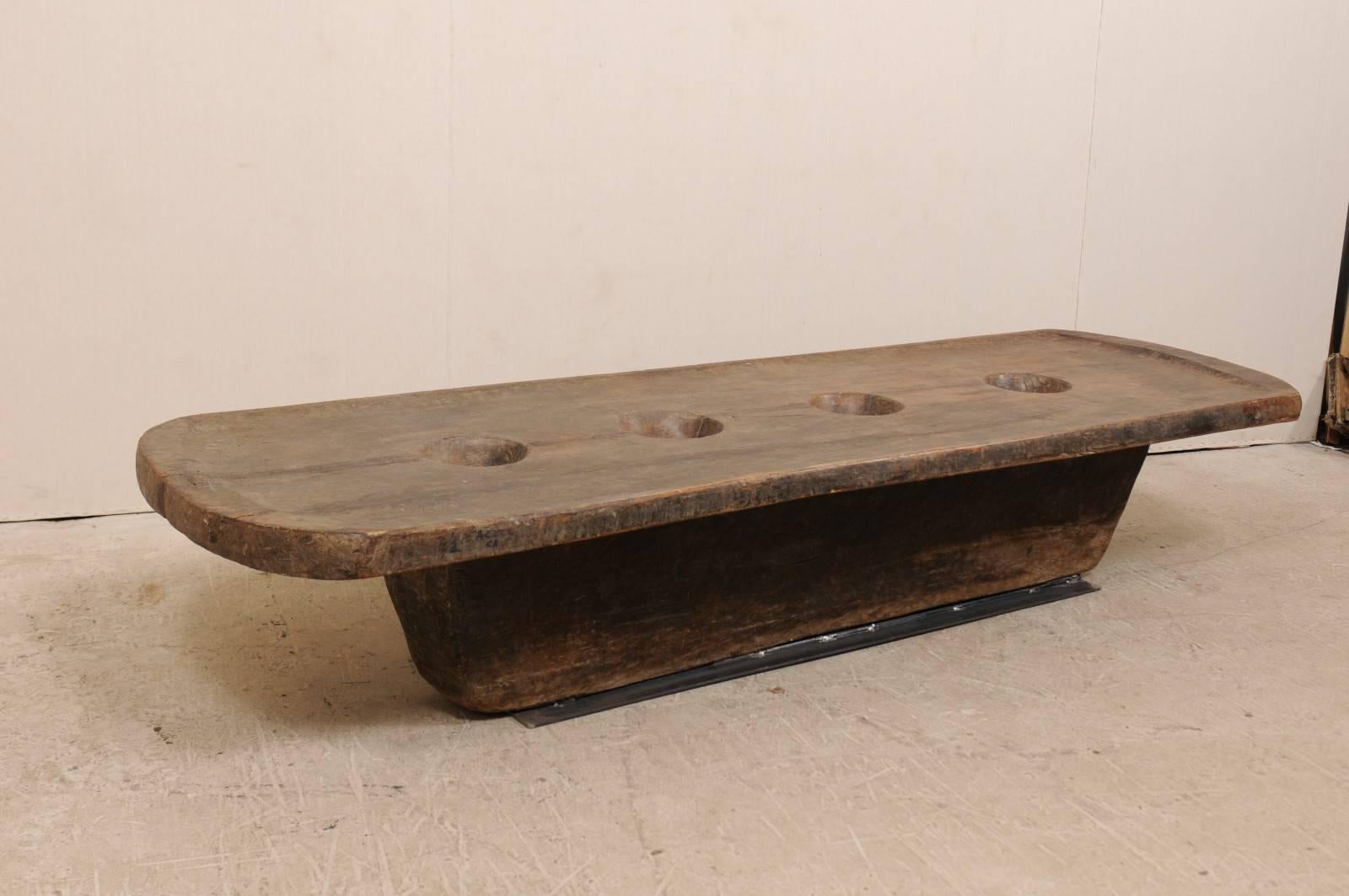 A Naga table from the late 19th-early 20th century. This primitive table from Nagaland, India was originally use by the Naga tribes of North East India as a grinding table, for grains such as millet. The four holes within the center are where the