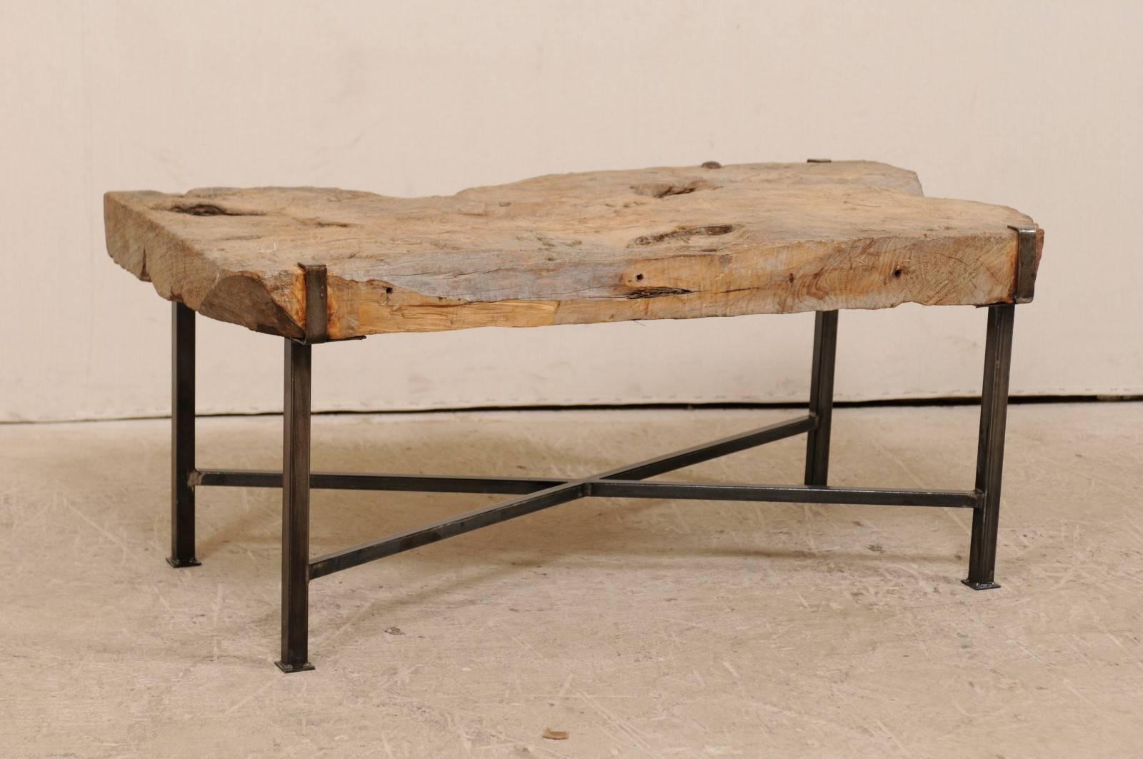 A 19th century Spanish wood slab coffee table on custom base. This coffee table has been fashioned from a 19th century Spanish thickly cut wood slab on a newer custom iron base. The slab top is supported by a custom black iron base, with four