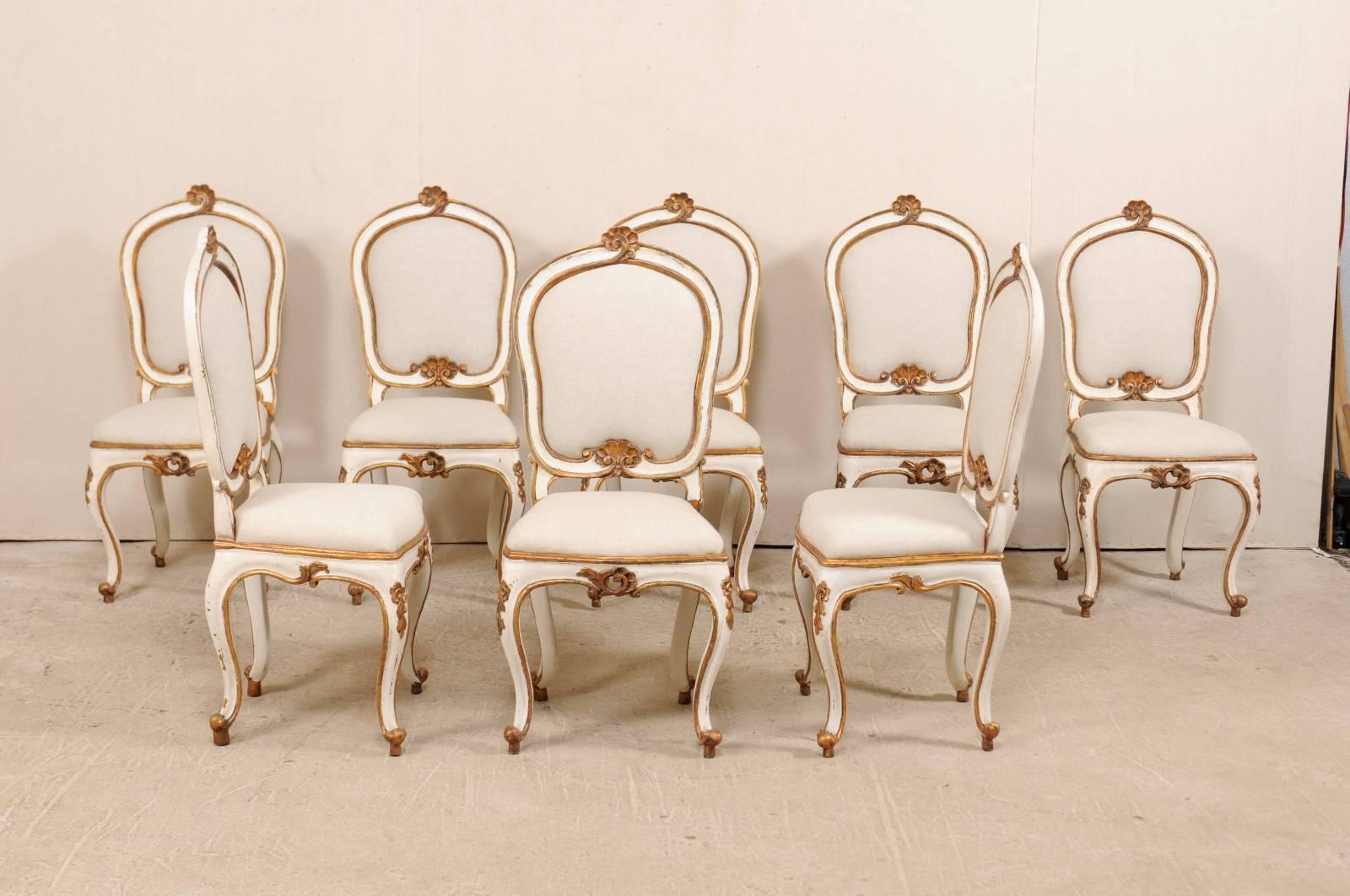 A set of eight Italian upholstered dining room side chairs from the early 20th century. This set of eight antique Italian chairs feature nicely carved fan and leaf motif details accenting their top and bottom back rails, knees, and pierced carvings