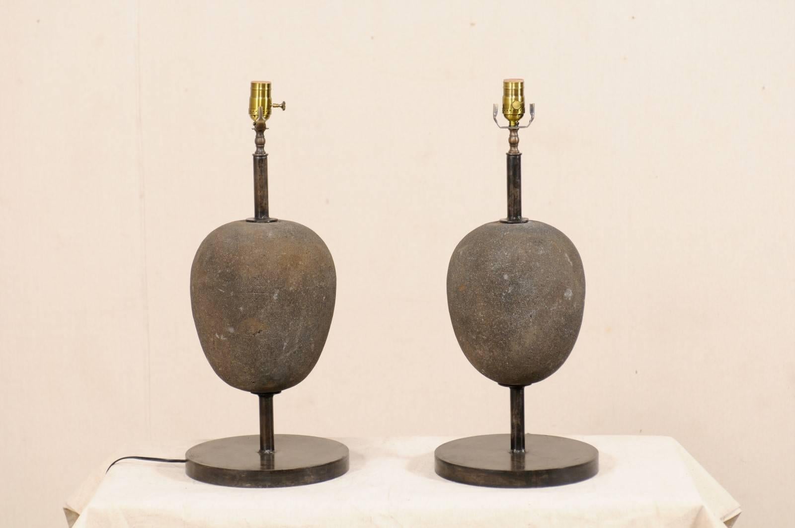 A pair of vintage European stone ovoid or egg-shaped table lamps. This pair of European table lamps have been custom fashioned from nicely carved egg-shaped stones which are mounted onto round-shaped iron bases. The stones have a