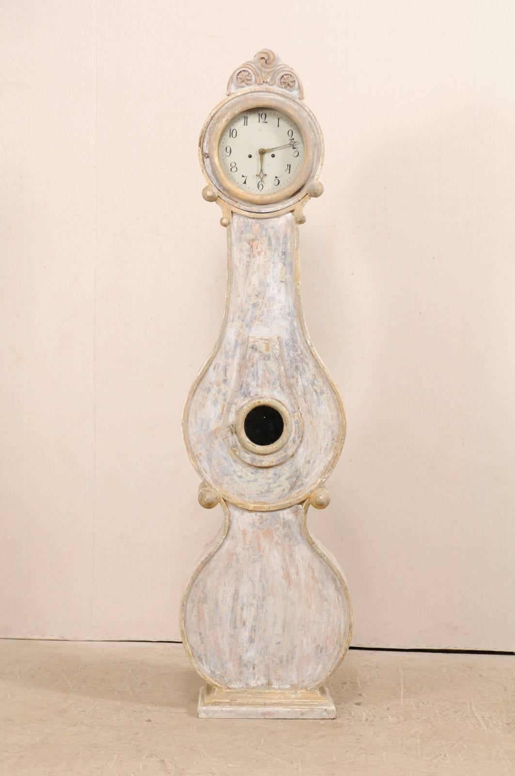 A 19th century Swedish Fryksdahl clock. This Fryksdahl clock features a carved crest with central volute atop of two stars, and scrolled accents flanking the neck and waist. This nicely curved clock, typical of the Fryksdahl style, has a bulbous