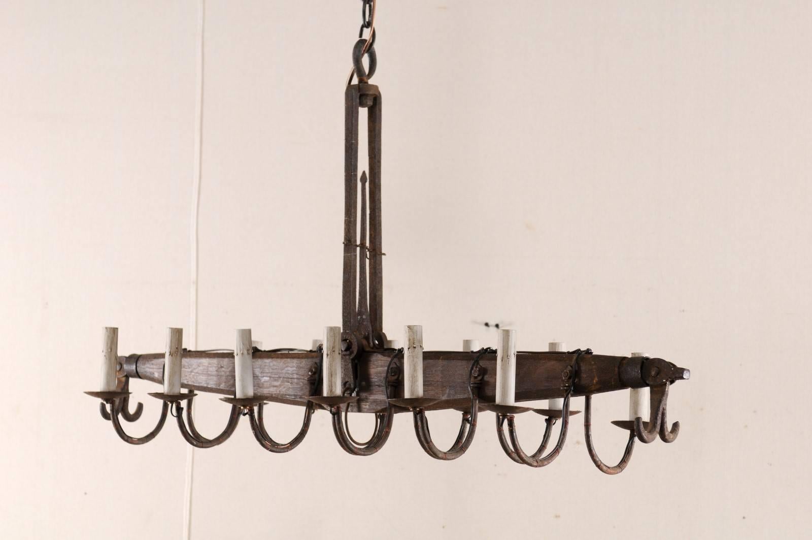 A French scale chandelier with twelve lights from the mid-20th century. This French chandelier features a central, linear-shaped beam from a mid-20th century scale with six lights along each side, making a total of twelve lights. Each iron light arm