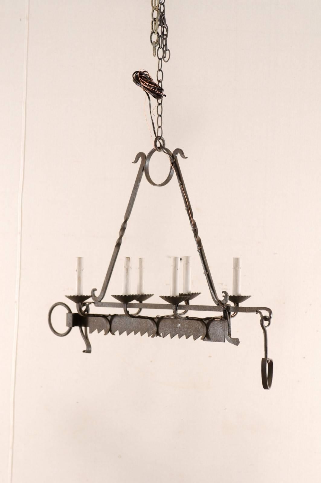 A French mid-century, six-light forged-iron chandelier made from a 19th century spit-jack. A spit-jack is a type of rotisserie that was once common in fireplaces. This chandelier has six arms, three rising up along each side, which connect to the