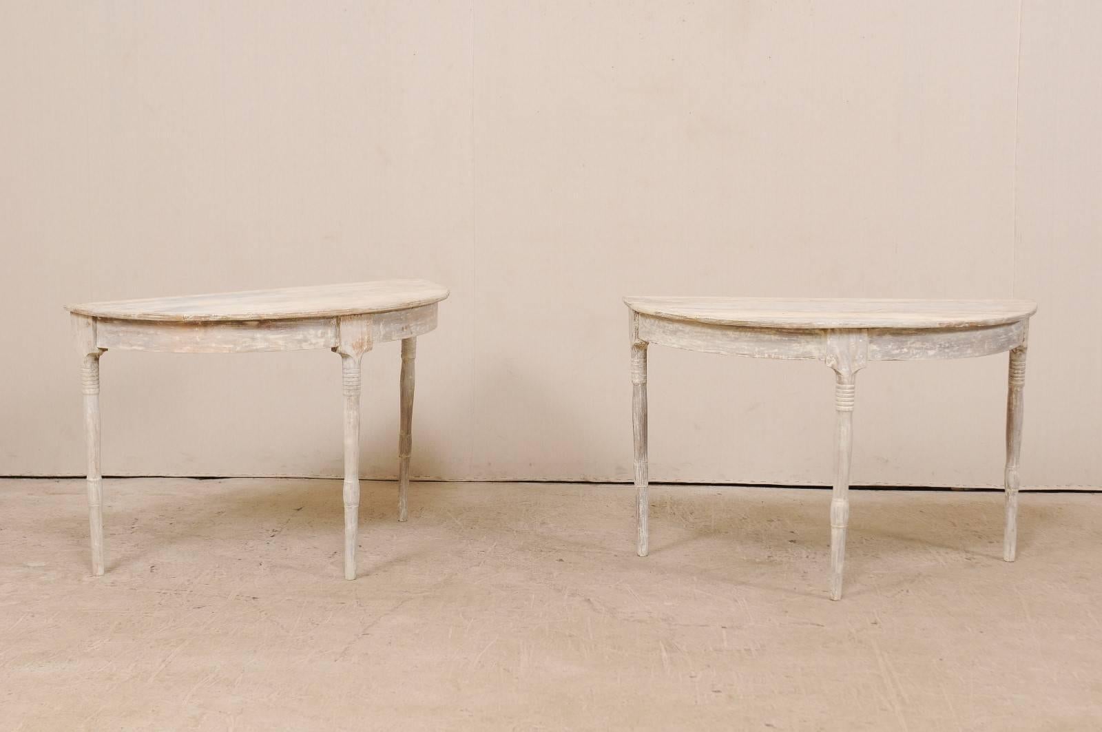 A pair of 19th century Swedish demilune tables. This pair of antique Swedish painted wood demi-lune tables features half moon tops over rounded aprons. The pair is raised on beautifully turned legs. These demi-lune consoles tables have a scraped