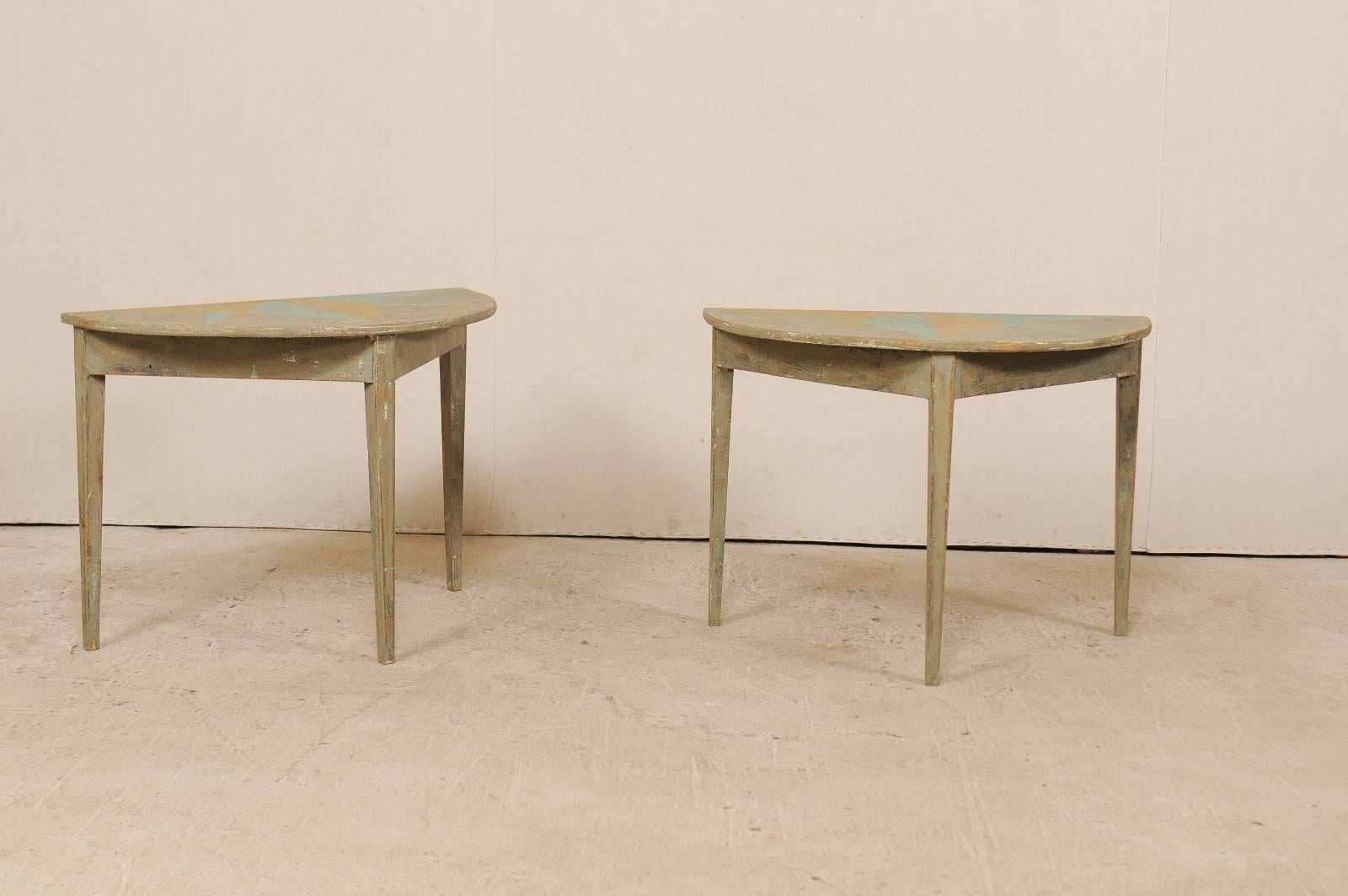 A pair of 19th century Swedish painted wood demilune tables. These antique Swedish demilune tables features a semi-circular top over a triangular shaped apron. Their tops have a custom painted half-star design in a turquoise and cantaloupe and the