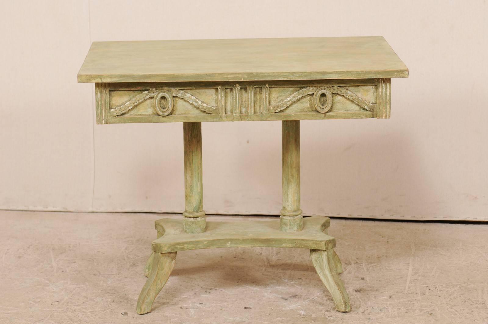 A Swedish 19th century Neoclassical painted wood Lindome style table. This antique Swedish console table features a richly decorated apron with leaved swags and wreaths, a rectangular-shaped top, and two column central pedestal style base. The