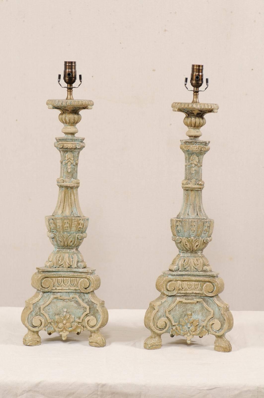 A pair of Italian style carved and painted table lamps. This pair of table lamps have been hand-carved and painted in the fashion of 18th and 19th century Italian candlesticks. They are decoratively carved in floral, leaf, and scroll motifs. Each of