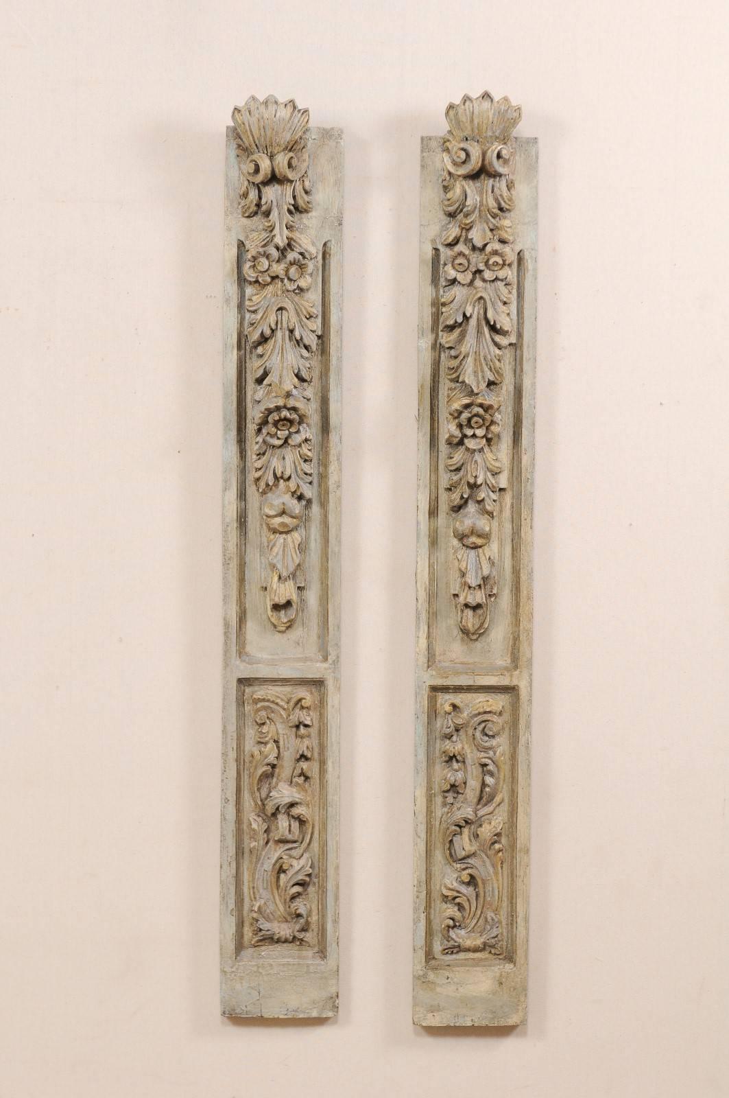 A pair of French hand-carved and painted wall plaques from the early 20th century. These antique French fragments, standing approximately 5 ft high, each having a vertically positioned rectangular-shape with three-dimensional carvings of florals,