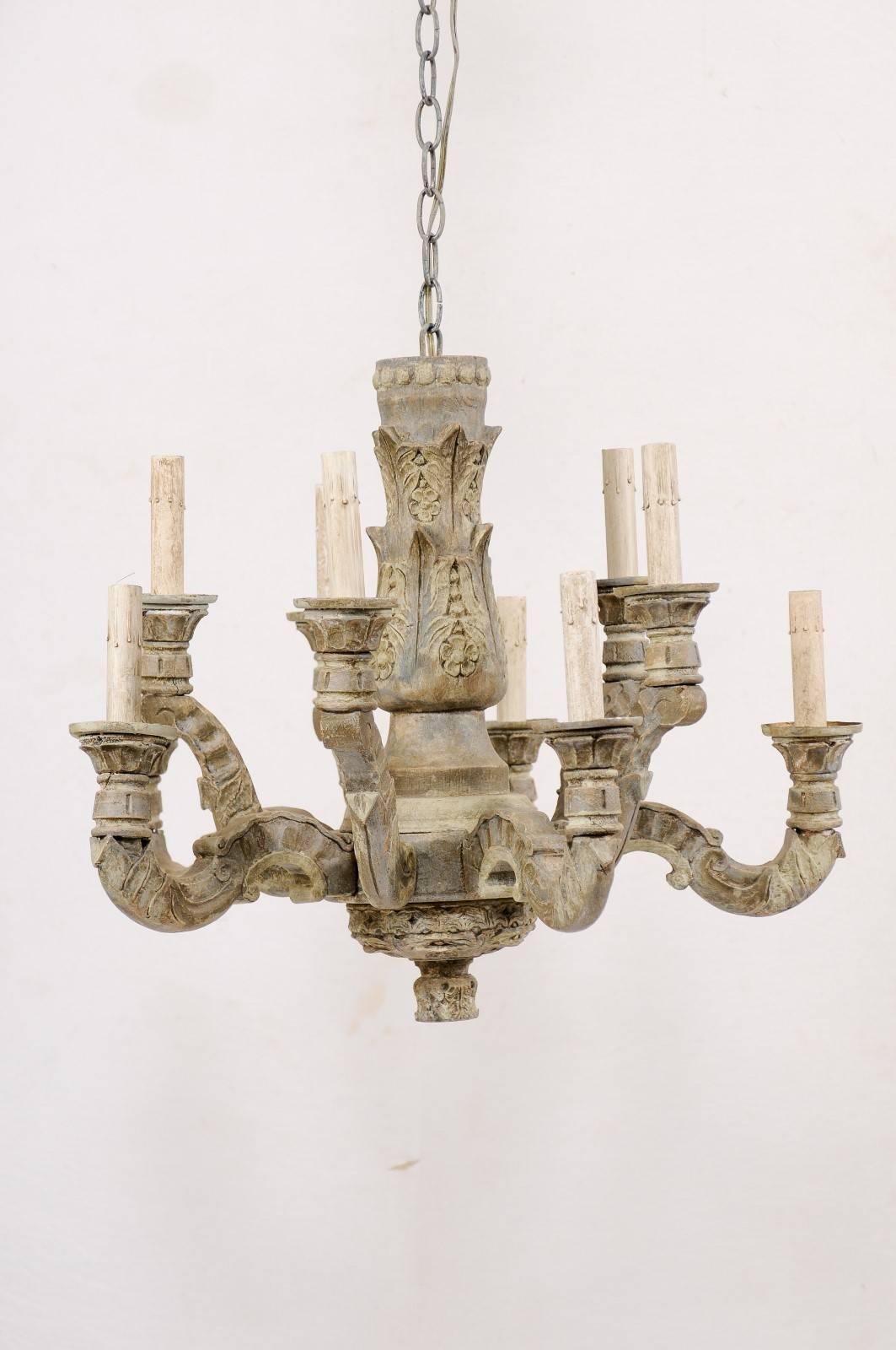 A French ten-light carved and painted wood chandelier from the mid-20th century. This vintage French chandelier has a thick, carved central column adorn in a motif of flowers and foliage with ten carved wood arms extending about it's perimeter at