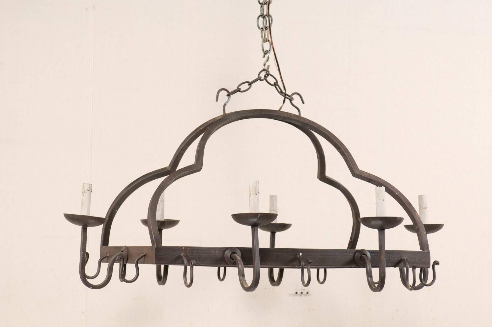A French mid-20th century six-light forged iron chandelier. This vintage French forged iron chandelier features a rectangular-shaped, grid interior body, with an dual-arching design connecting each of its four corners to the upper canopy, creating a