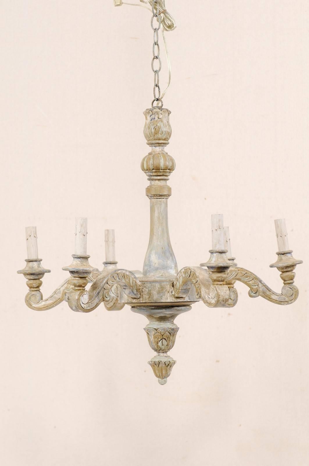 A vintage French painted wood six-light chandelier. This French chandelier from the mid-20th century features a central column body with carved foliage motif and a circular belly from which six scrolled and carved acanthus leaf wrapped arms extend