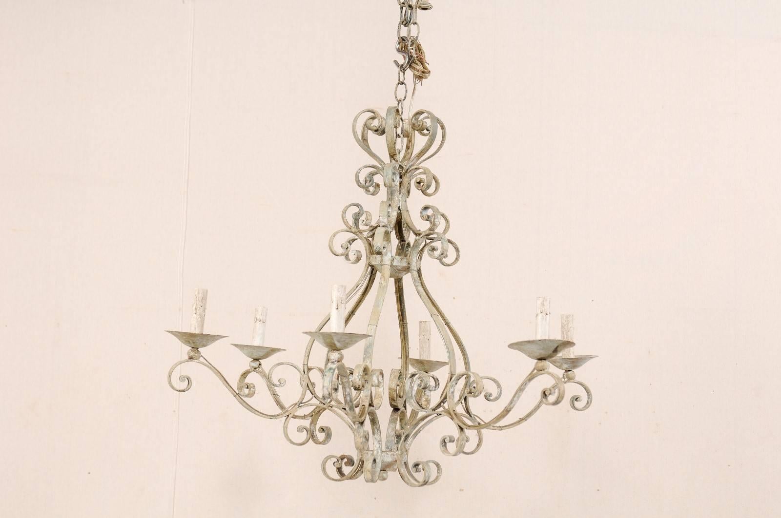 A vintage French heavily scrolled and painted six-light chandelier. This ornate French chandelier from the mid-20th century features a series of decorative S-scroll and C-scroll motifs throughout. Six scrolled arms lead out to their metal bobèches
