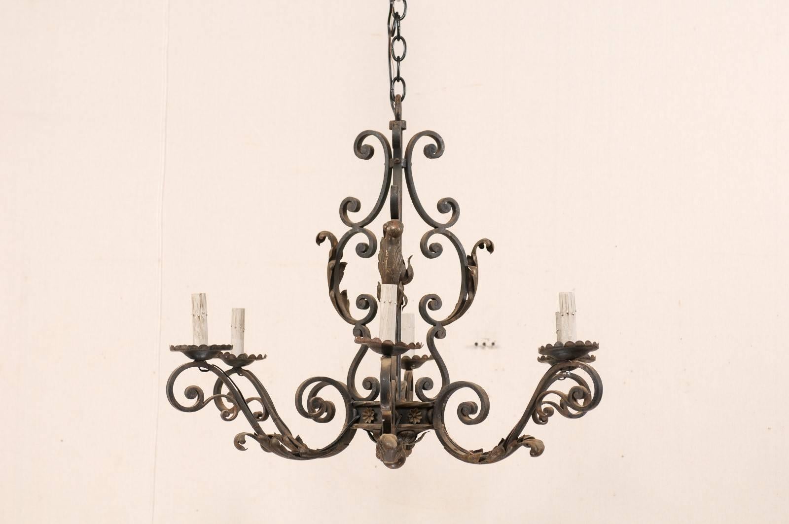 A French iron six-light chandelier from the mid-20th century. The armature of this vintage French chandelier is comprised of a series of C-scroll and S-scrolled forged iron motifs, decorated with acanthus leaves and small flowers. Each of the six