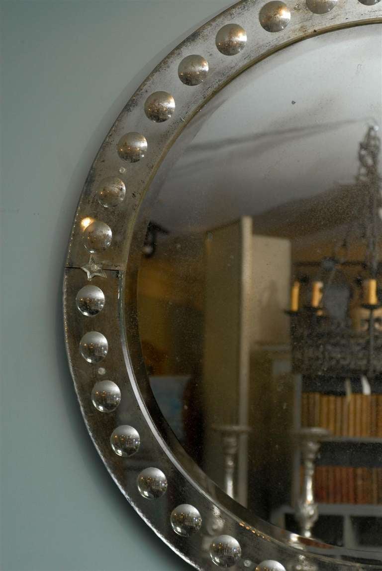 The round bullseye Venetian style mirror. With its circular shape and assortment of small size bullseye motifs in its surround, as well as star ornaments marking its cardinal points, this Venetian style mirror is the perfect focal point for a living
