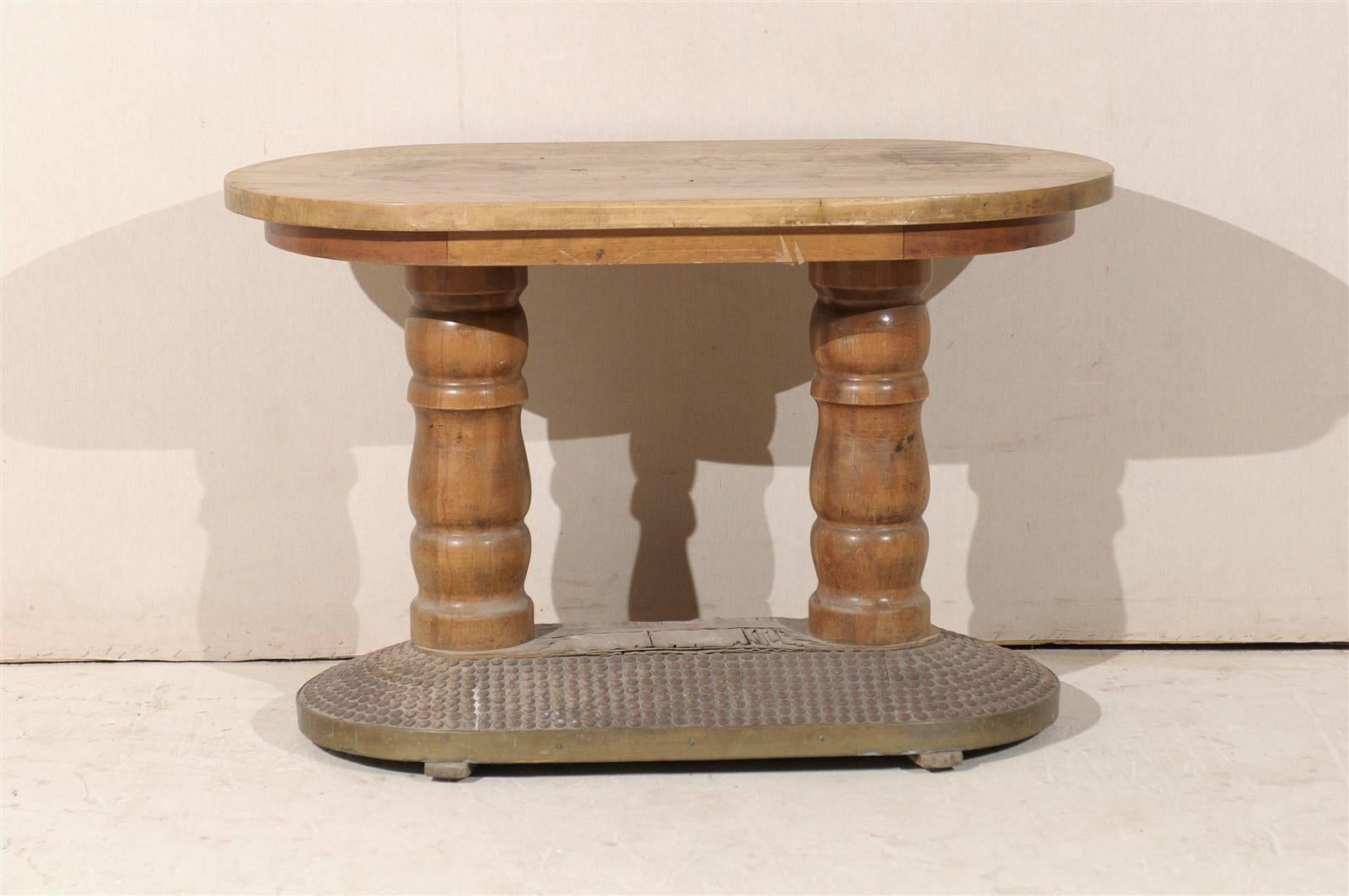 A French early 20th century oval wooden console table with turned legs and interesting wooden base decorated with thick nail heads.
